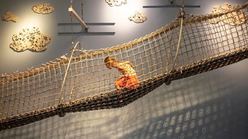 Child crawling through the rope net of the climbing schooner exhibit