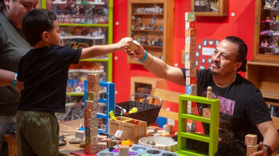 Child stacking wooden blocks with an adult at Michael's Museum