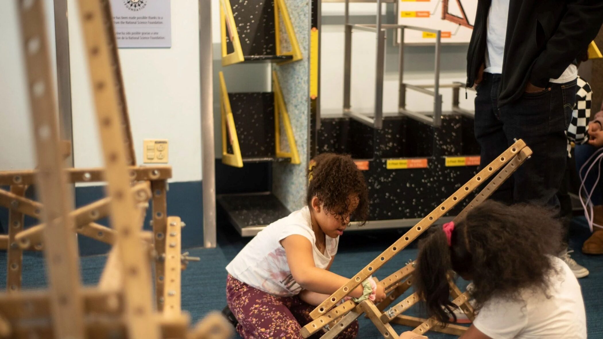 Children building a structure with wooden beams in the Skyline exhibit