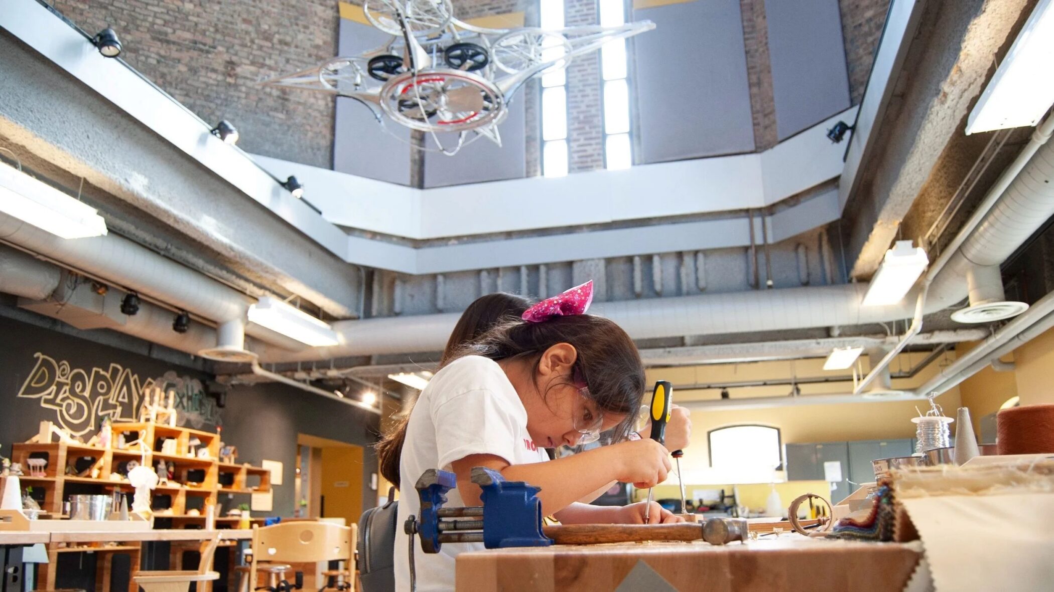 Children using tools at a workbench in the museum Tinkering Lab