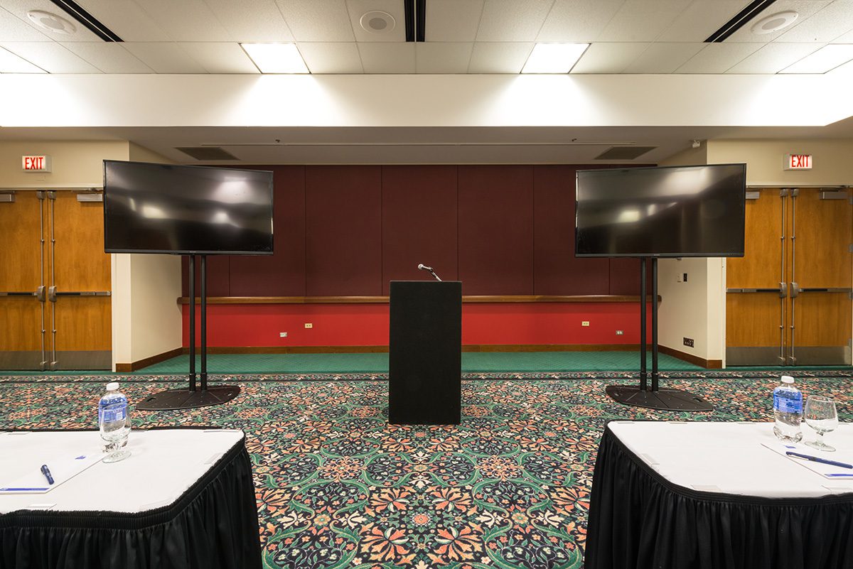 A Meeting Room With Two TV Screens & A Podium In The Middle