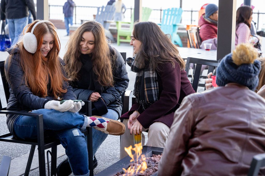 group of women laughing and sitting by the fire pits outside