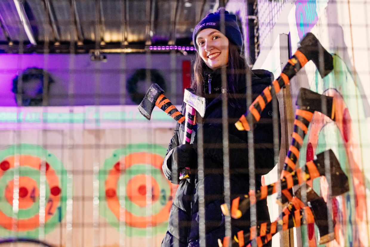 Young woman standing inside axe throwing cage at Navy Pier.