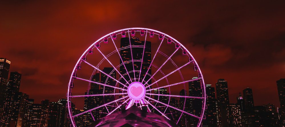 Centennial Wheel with a heart and pink lights.