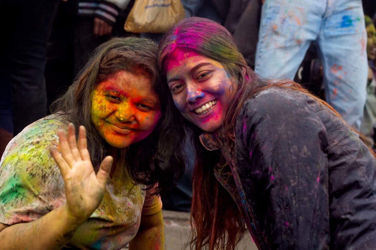 Girls covered in colorful paint at Holi celebration.