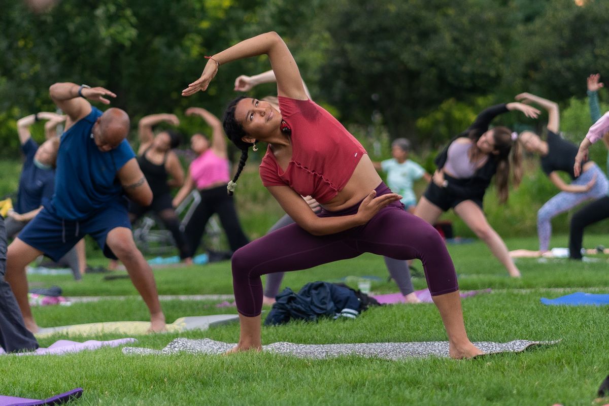 Navy Pier Pier Fitness yoga participants holding side stretch on grass