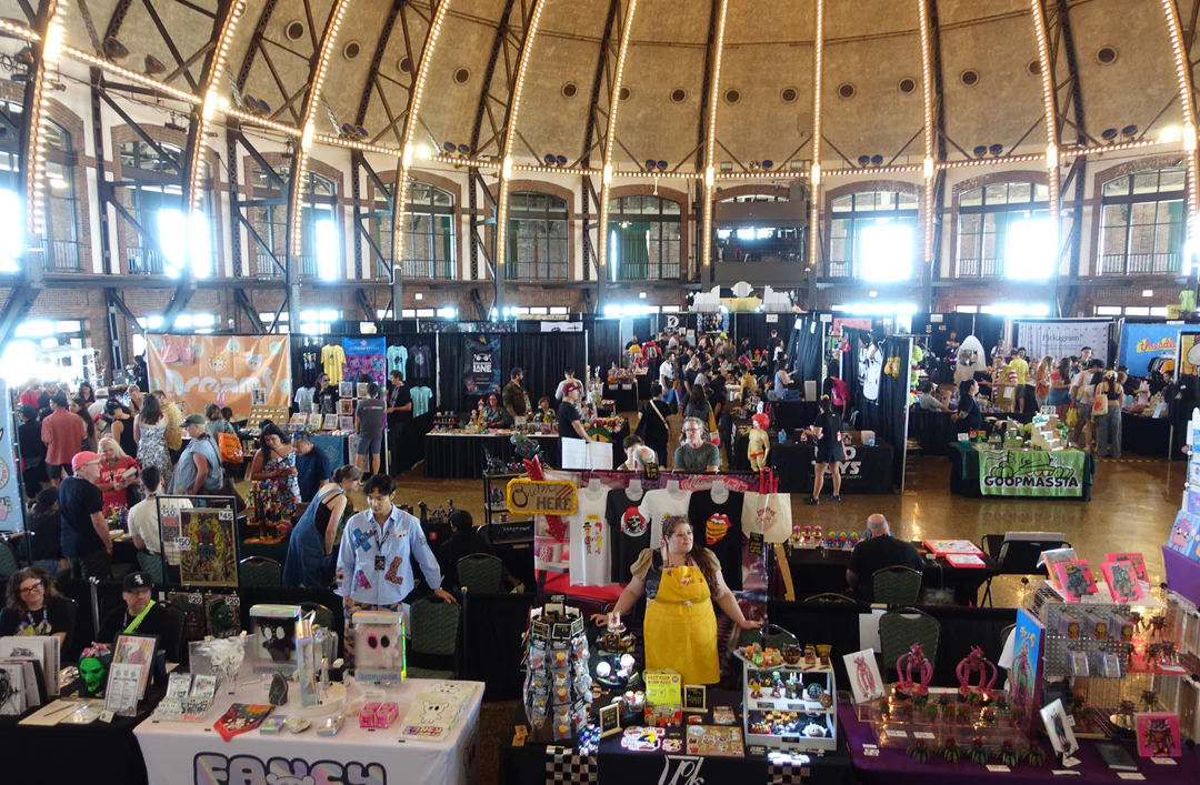 Wide view of a crowded indoor event at Navy Pier with vendor tables and visitors under a domed ceiling