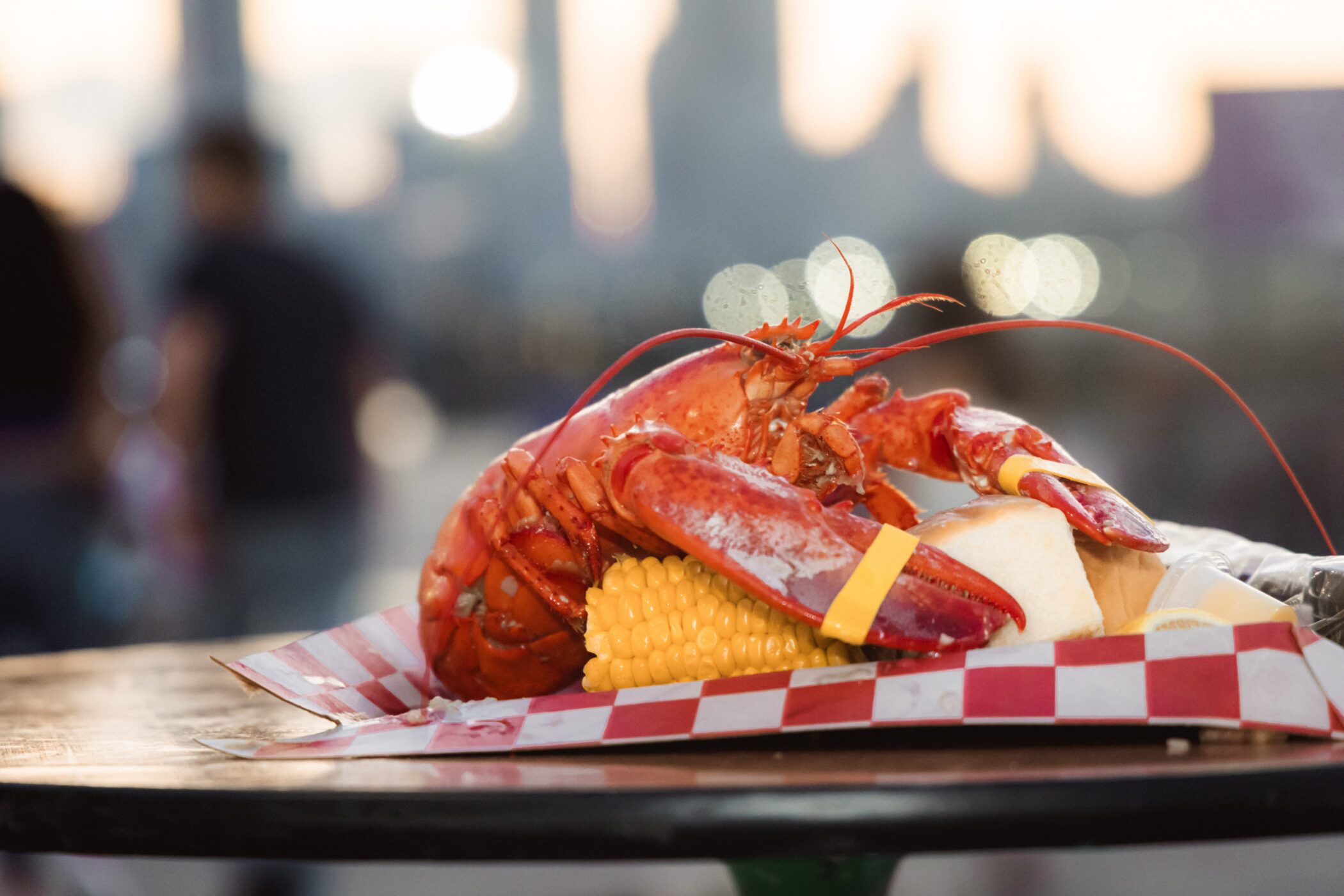 Whole lobster with corn and bread on a tray on a table