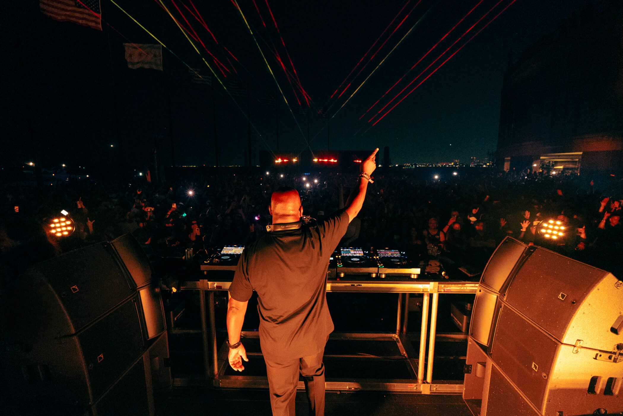 Carl Cox performing at Navy Pier's Open Air concert, with vibrant laser lights and a cheering crowd.