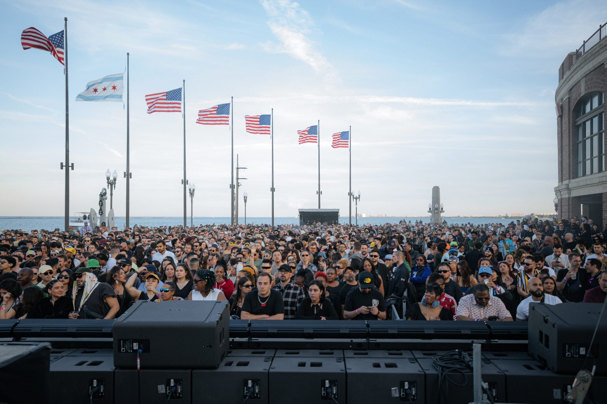 crowd enjoying an event at Navy Pier's East End Plaza with flags waving