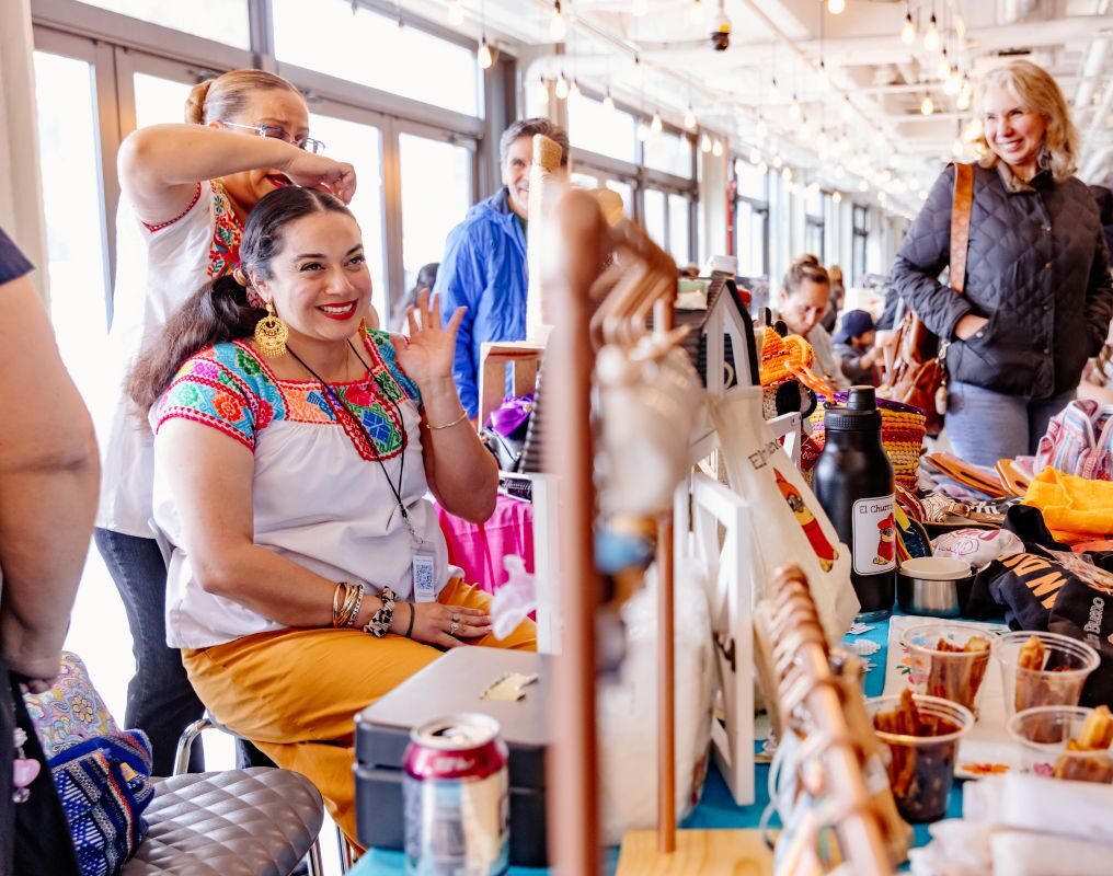 Smiling vendor at Navy Pier's Mexico Fest showcasing crafts and snacks.