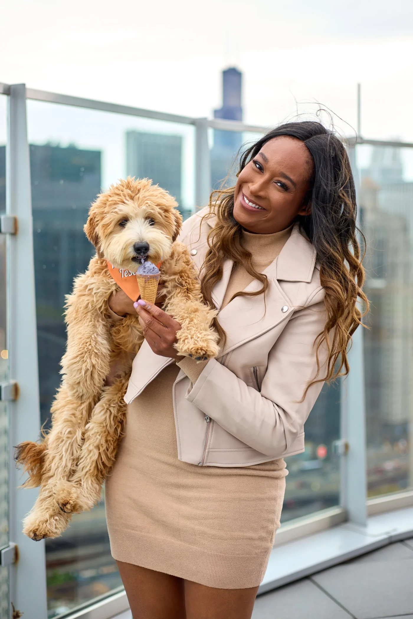Woman holding a small dog eating a cone of ice cream in outdoor setting