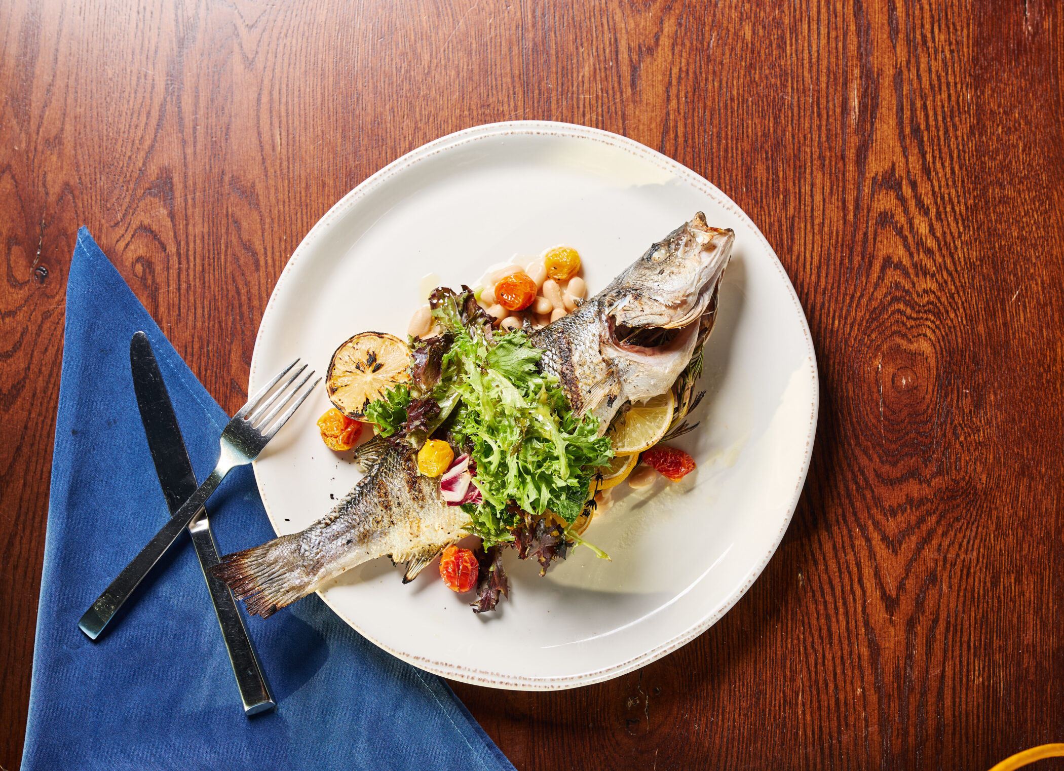 Grilled branzino with fresh greens and lemon on a plate at Lirica Navy Pier