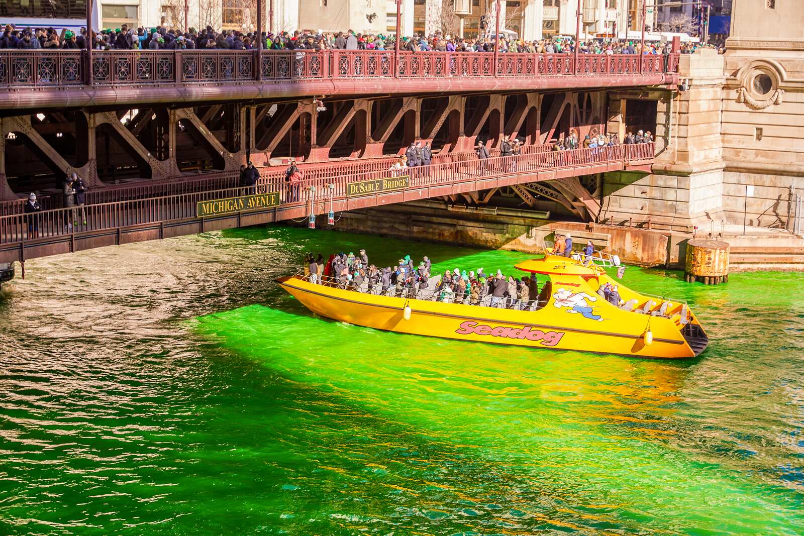 Yellow tour boat on the green Chicago River near Michigan Avenue bridge