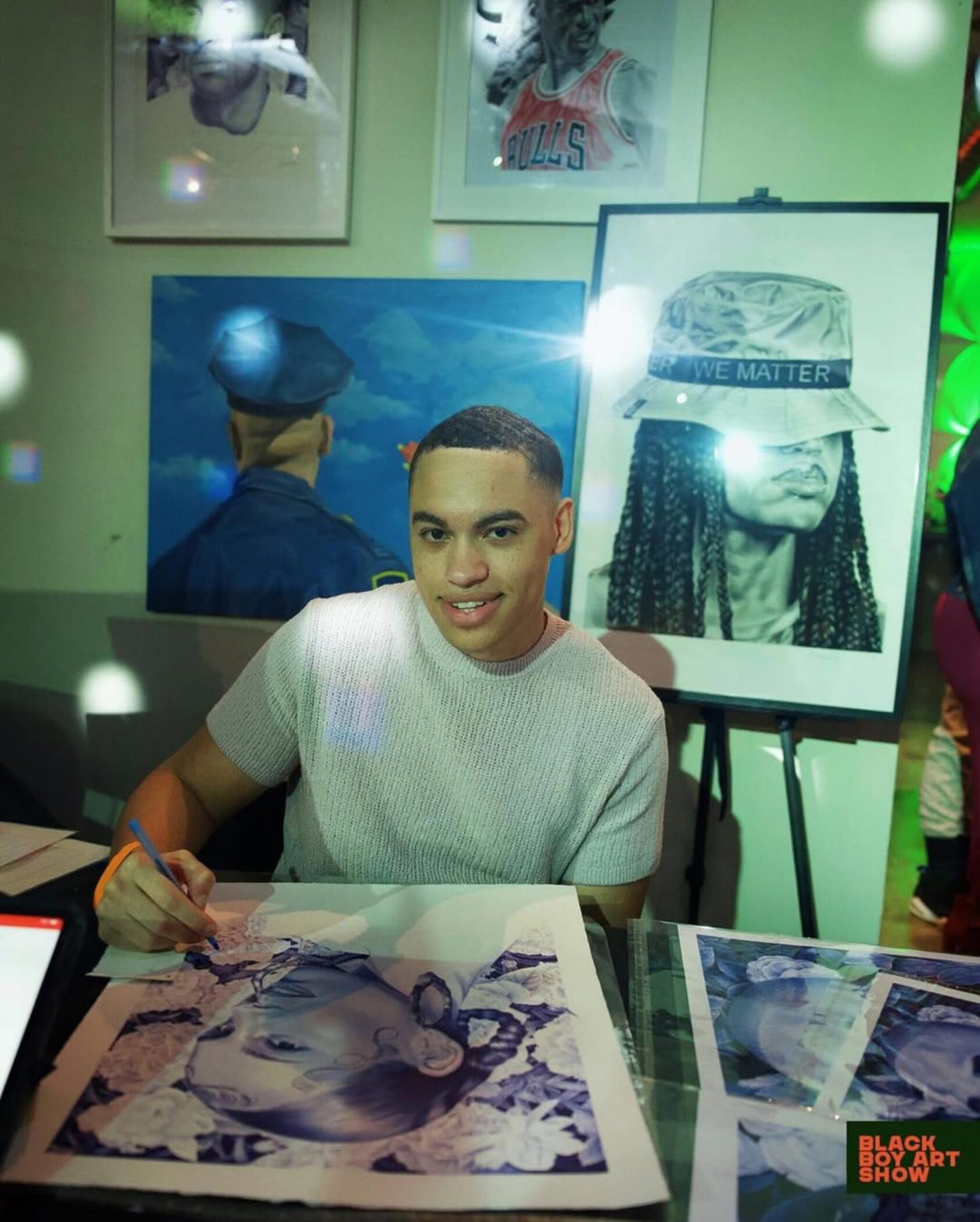 Artist drawing detailed artwork with displayed pieces at Navy Pier