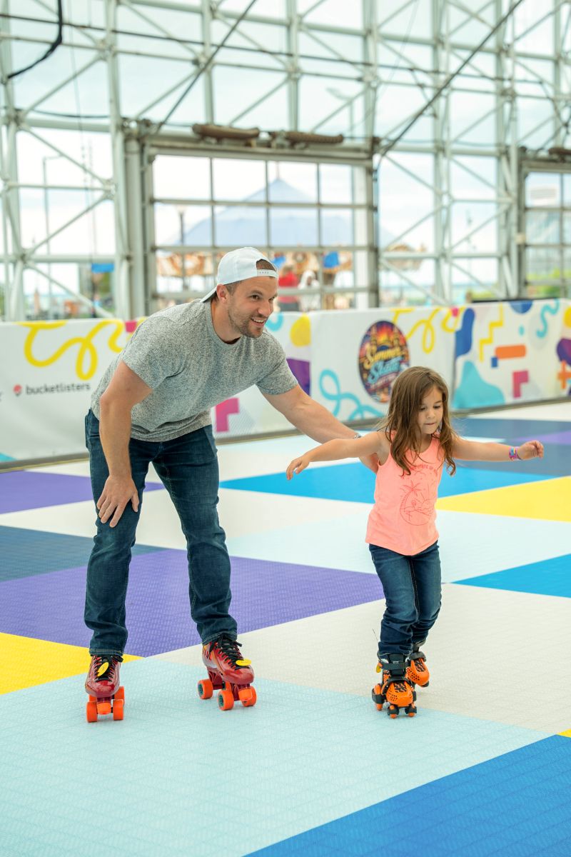 Adult helping a child learn to roller skate at Summer Skate