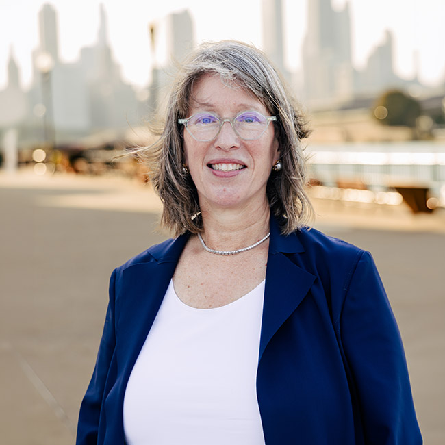 Headshot of Jennifer Steans in a navy blazer with the skyline behind