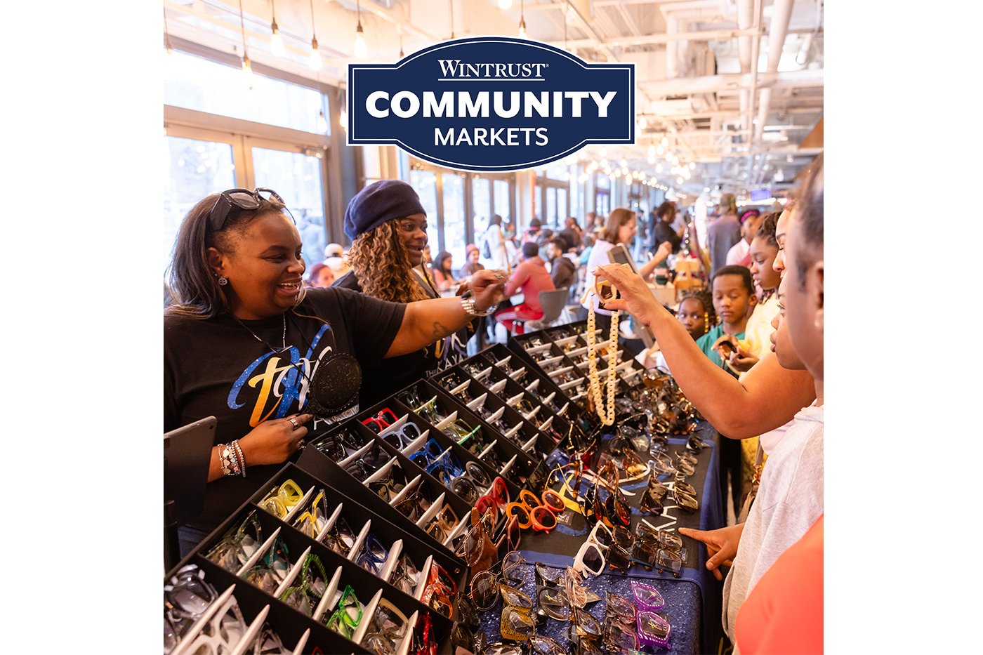 Shoppers browsing jewelry at a busy Wintrust Community Markets stall