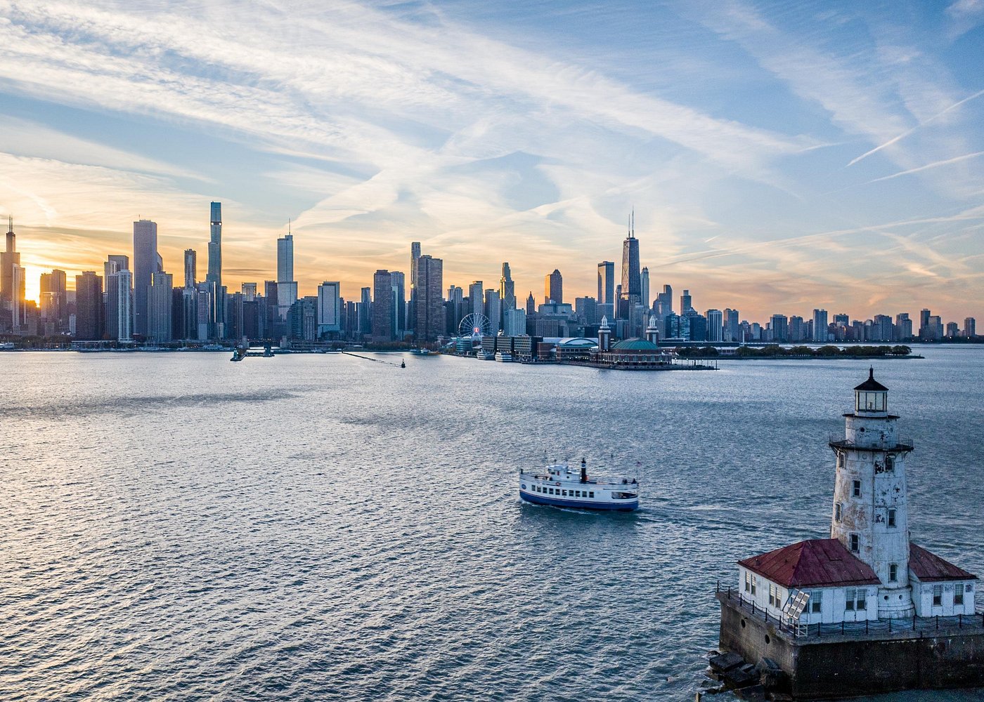 Shoreline boat and harbor lighthouse at sunset with the Chicago skyline
