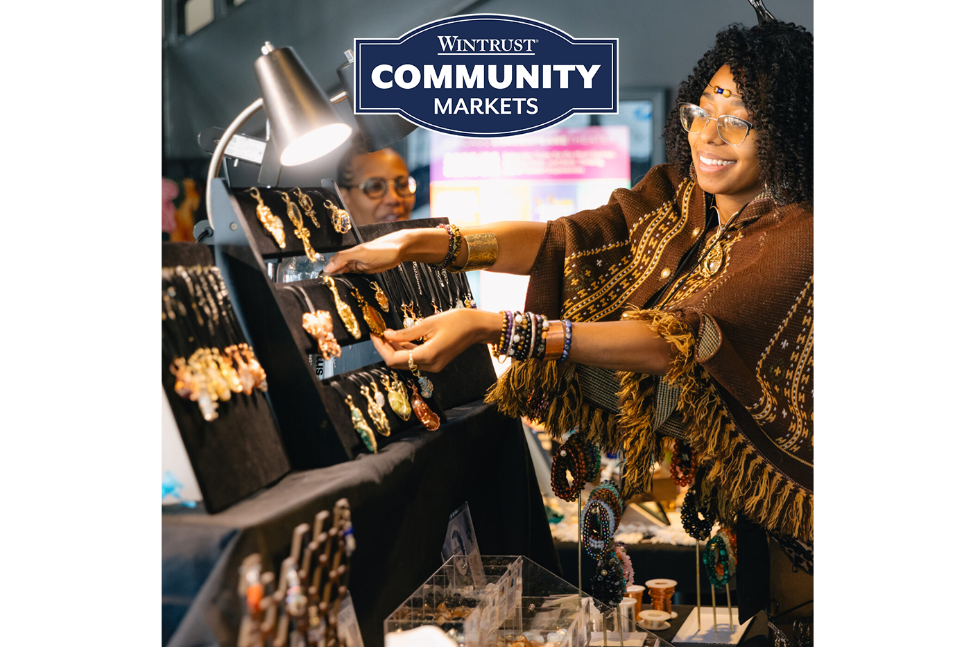 Vendor arranging a jewelry display at a Wintrust Community Markets stall